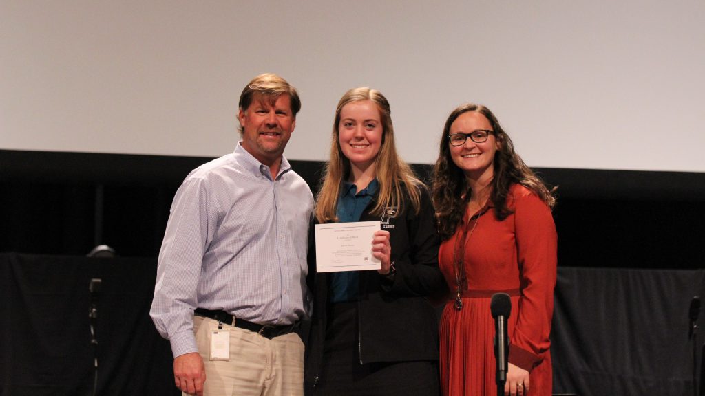 Jade Hannan, a National Merit Finalist, standing next to a man and woman, both holding a certificate.
