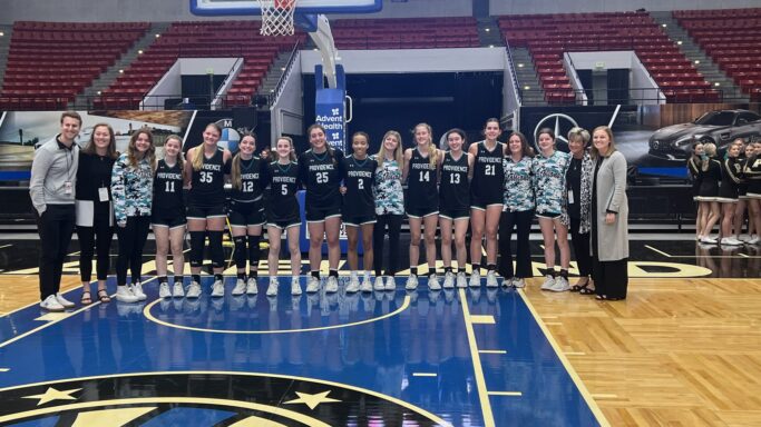 The girls basketball team is posing for a picture on the court during their historic season.