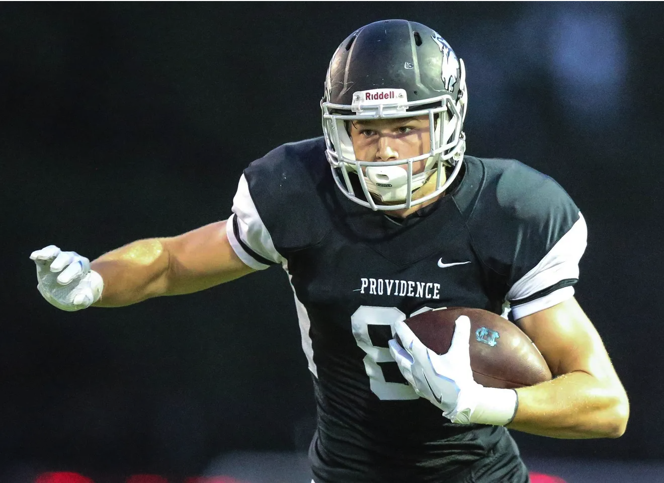 Mallory, a drafted NFL football player, is running with the ball.