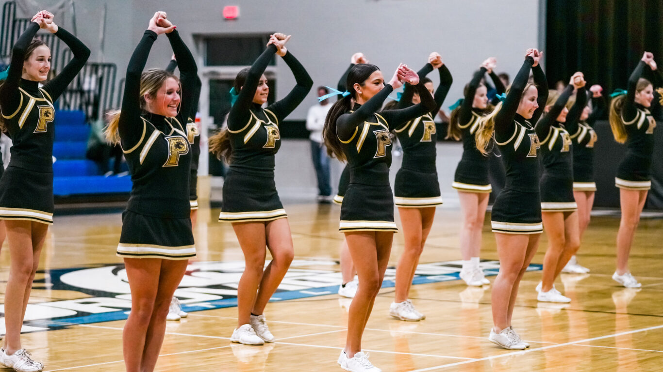 A group of cheerleaders performing at a home basketball court.