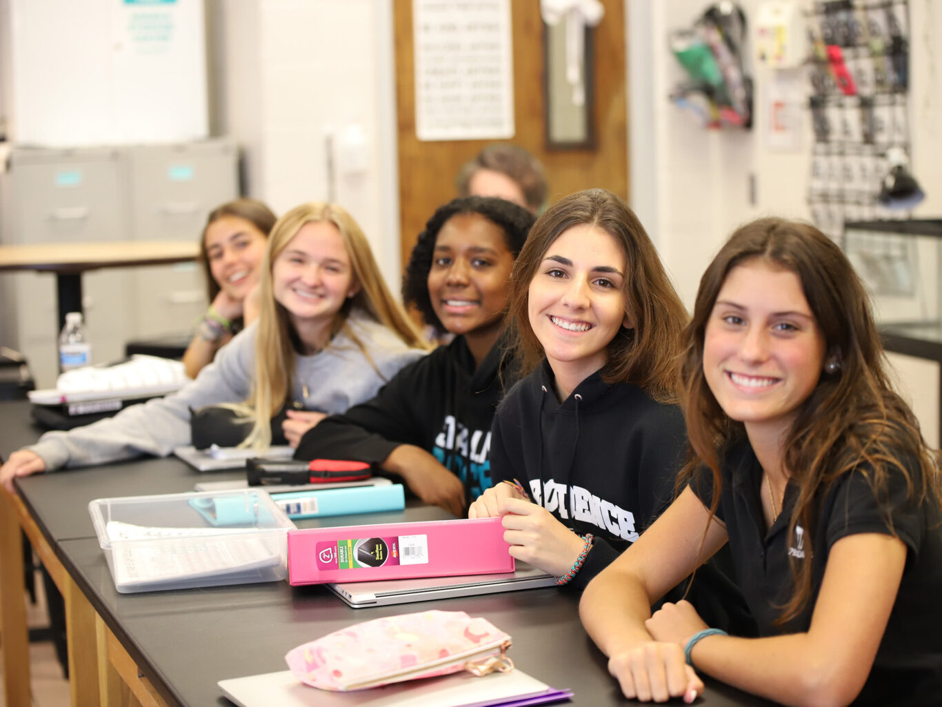 A group of girls sitting at a table in a classroom.