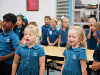 A group of Lower School children singing in a classroom.