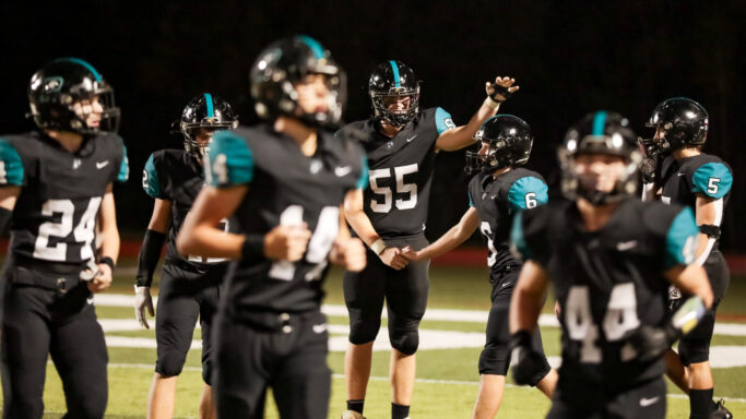 A group of football players on the field at night, engaging in a thrilling match.