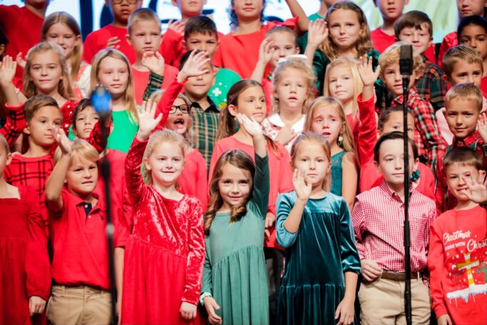 A group of Lower School children singing in front of a microphone.