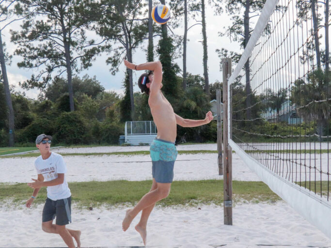 Two men playing volleyball on the sandy court.