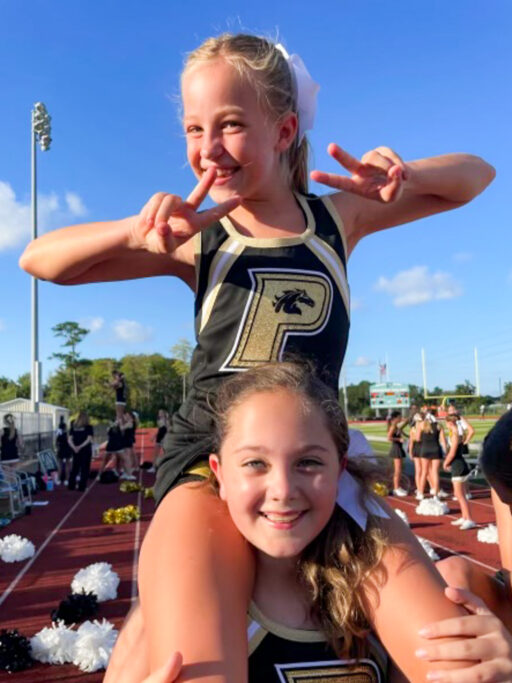 Two cheerleaders showcasing student life on a field.