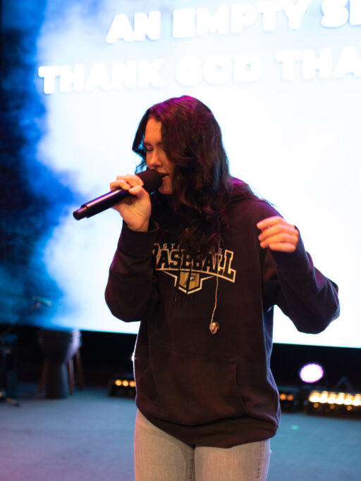 A woman uplifting her spiritual life by singing into a microphone.