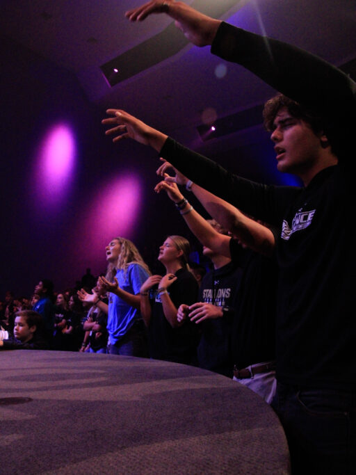 A group of people engrossed by the spiritual life of a man on a skateboard.