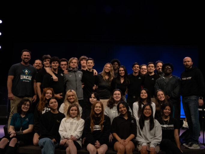 A digital arts group posing for a photo on stage.