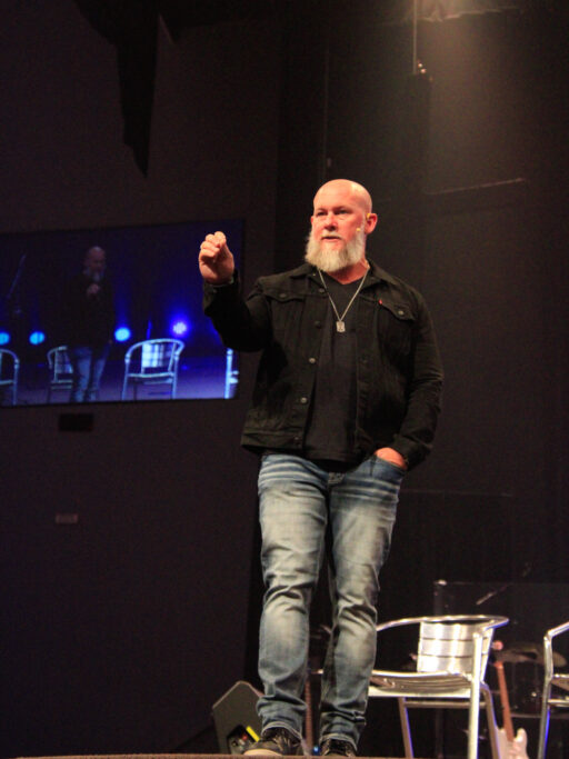 Joby Martin standing on a stage presenting to student chapel service.