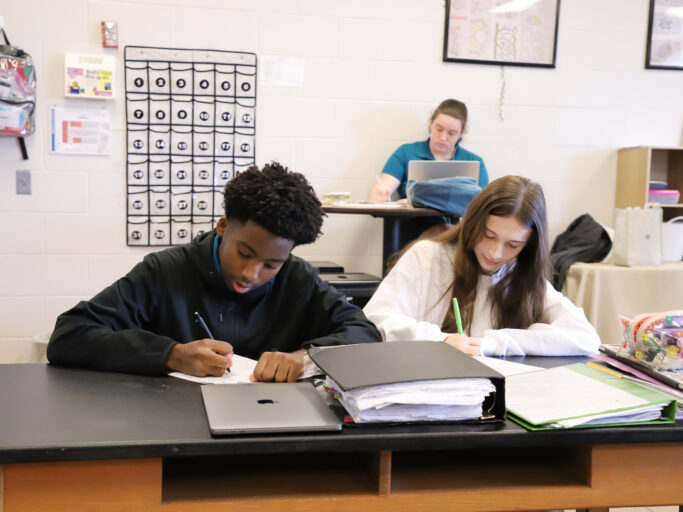 Two students receiving academic support in a classroom.