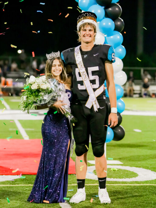 A man and woman enjoying a student life moment on a football field with confetti.