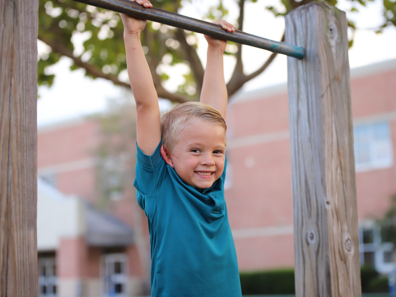 A young boy demonstrating leadership by performing pull-ups on a pull-up bar.