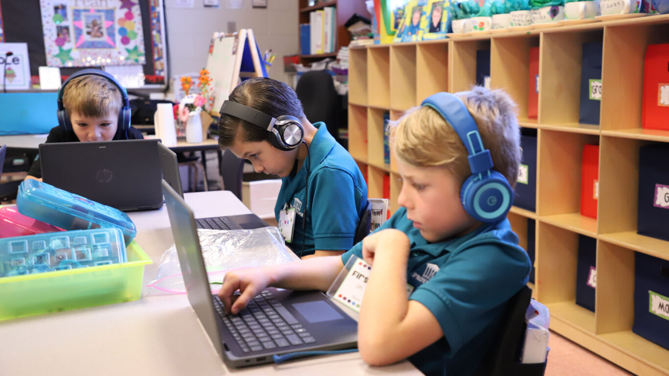 A group of children utilizing technology in a classroom.