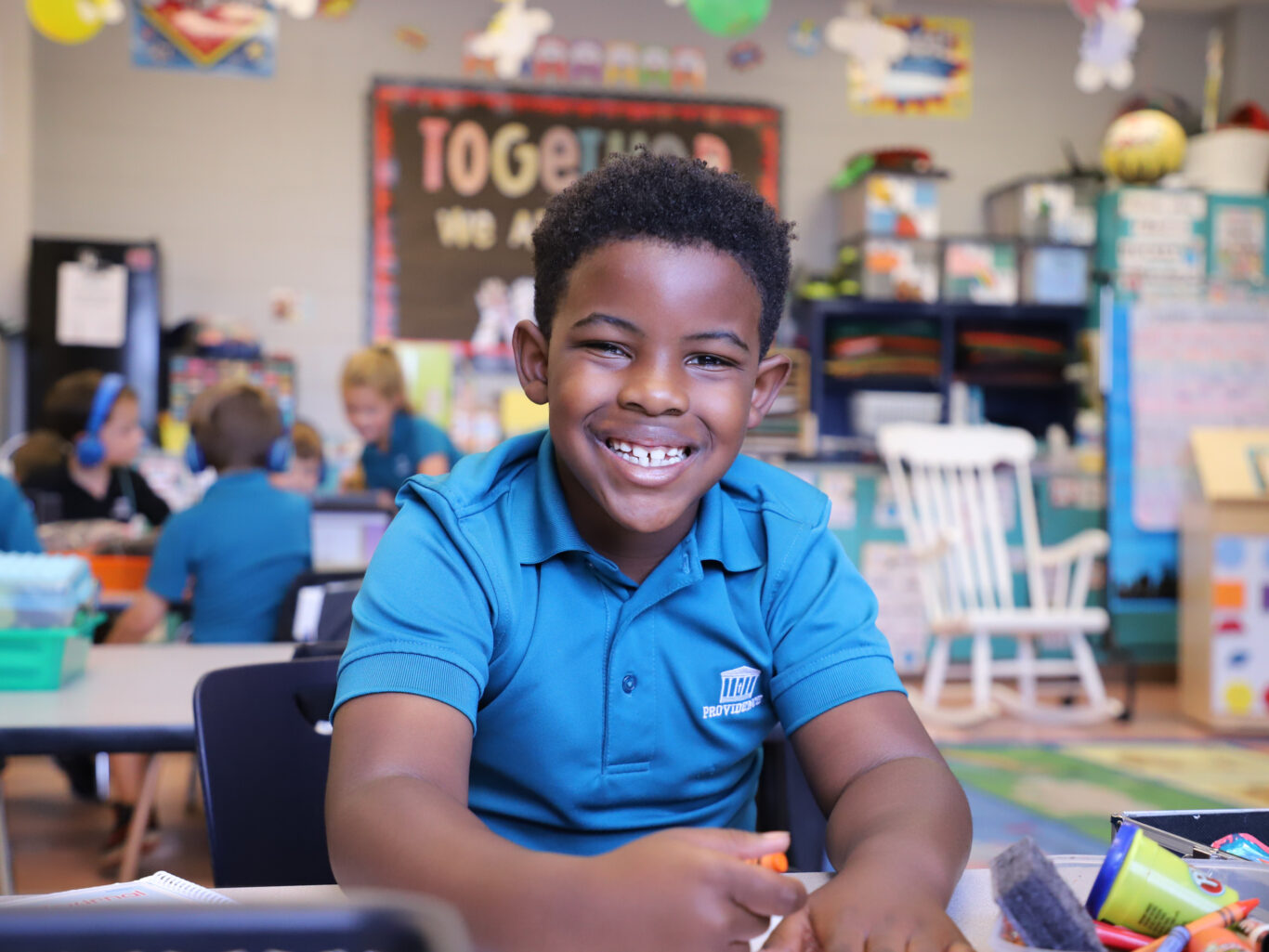 A young boy smiling at a desk in a classroom, showcasing his enthusiasm for learning and future employment prospects.