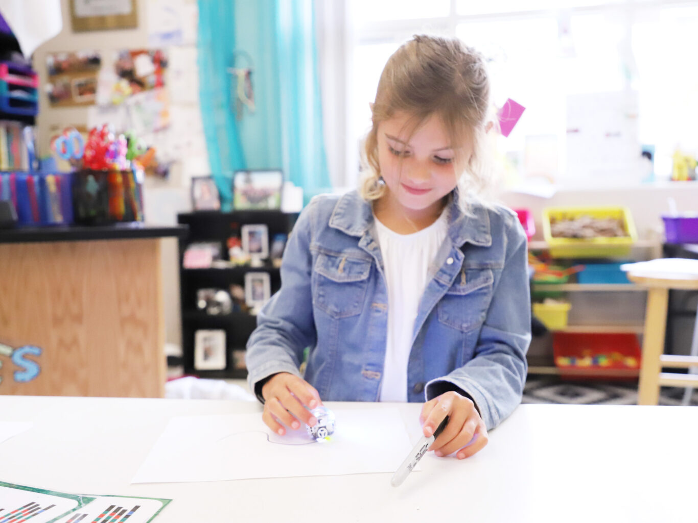 An employed girl is sitting at a table in a classroom.