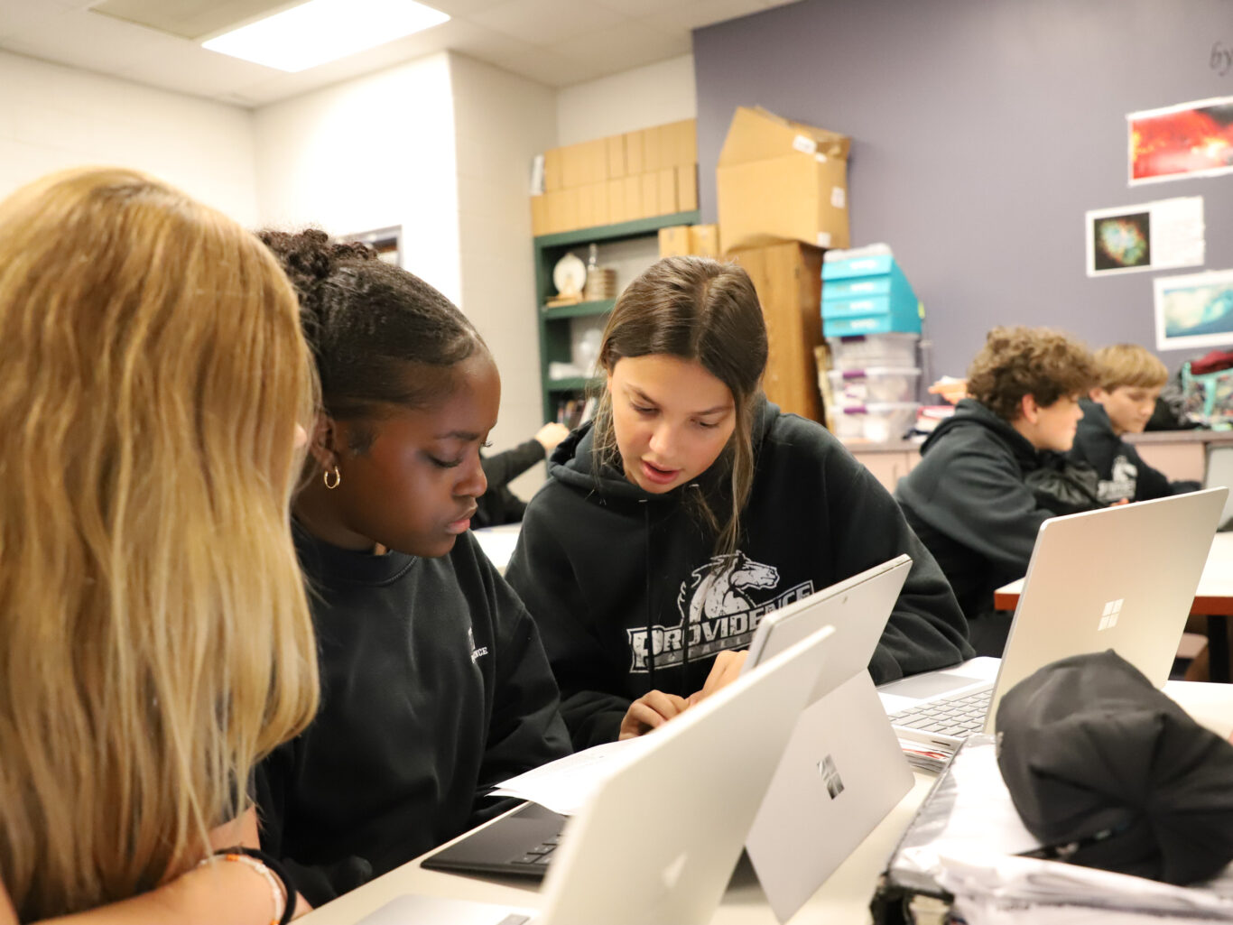 A group of girls working on laptops in a fine arts classroom.