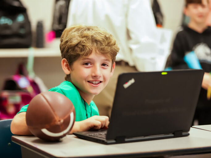 A boy wearing a green shirt with technology.