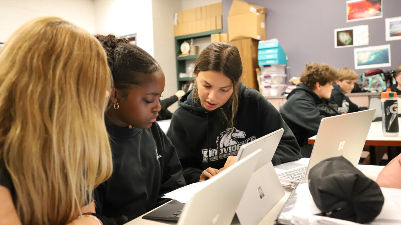         Description: Digital arts students working on laptops in a classroom.