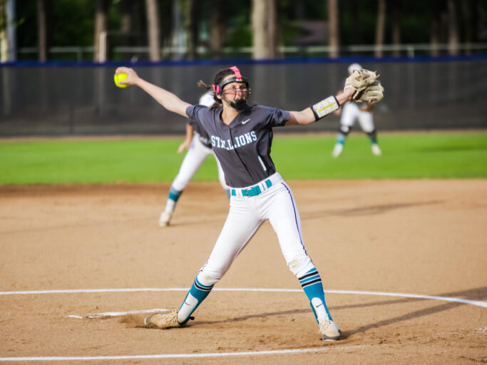 A softball player throwing a ball on a field at the facilities.