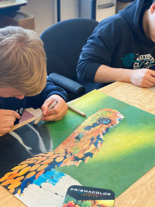 Two boys working on a Fine Arts painting in a classroom.
