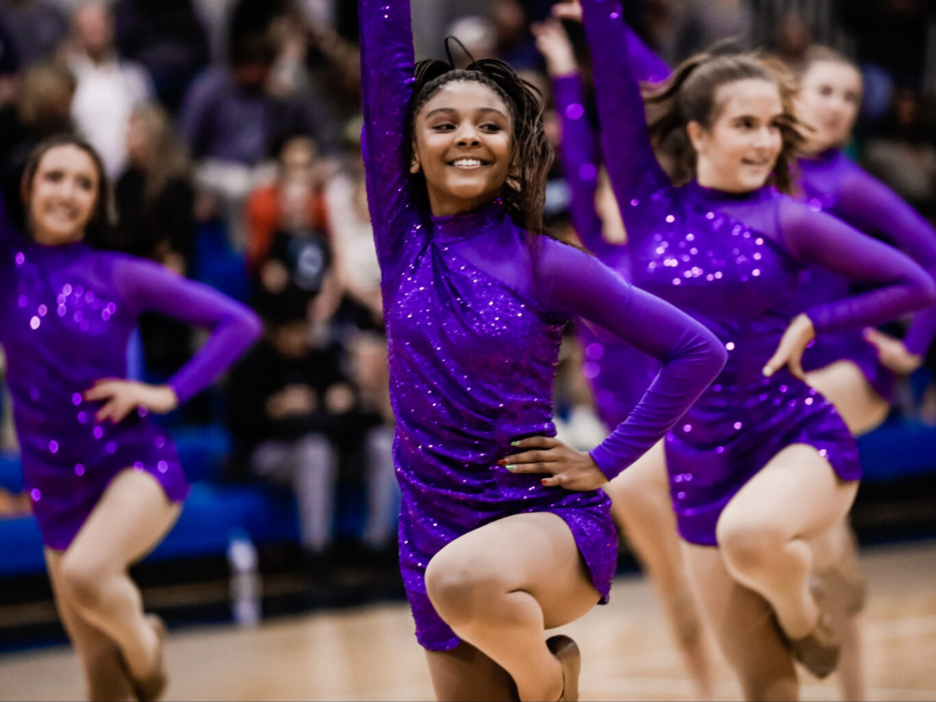 A group of cheerleaders visually performing on a basketball court.