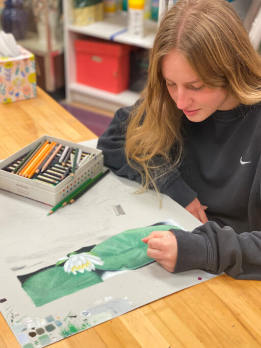 A girl is passionately engaged in the act of drawing, showcasing her talent for fine arts on a piece of paper.