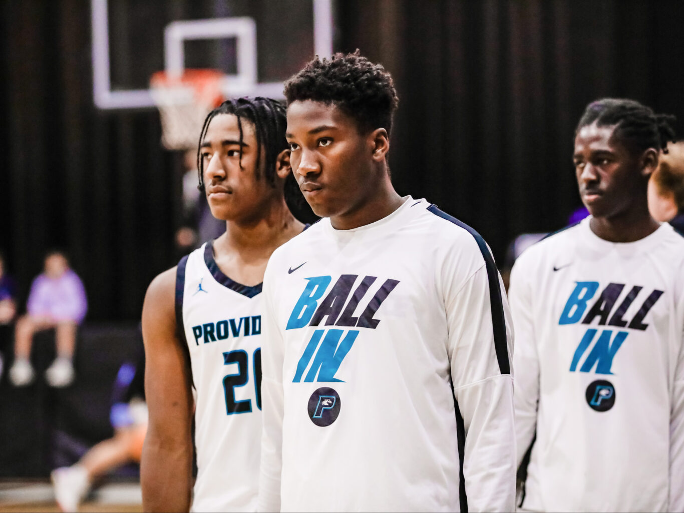 Three young boys standing next to each other on a basketball court.