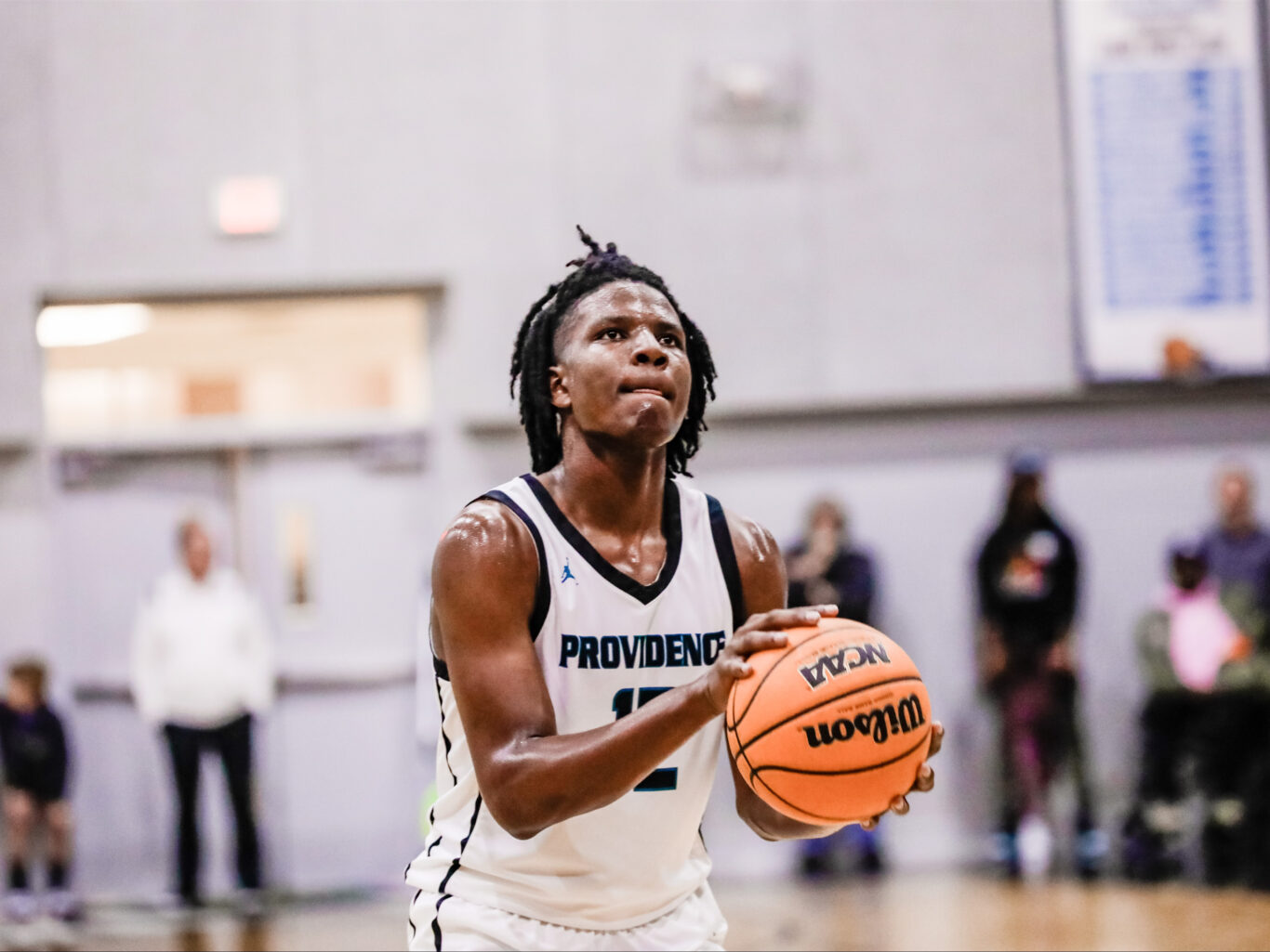 A basketball player with dreadlocks holding a ball, showcasing their skills in the sport.