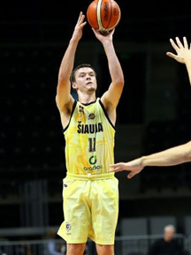 A college basketball player in a yellow uniform shoots the ball.