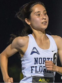 A college girl running on a track at night.