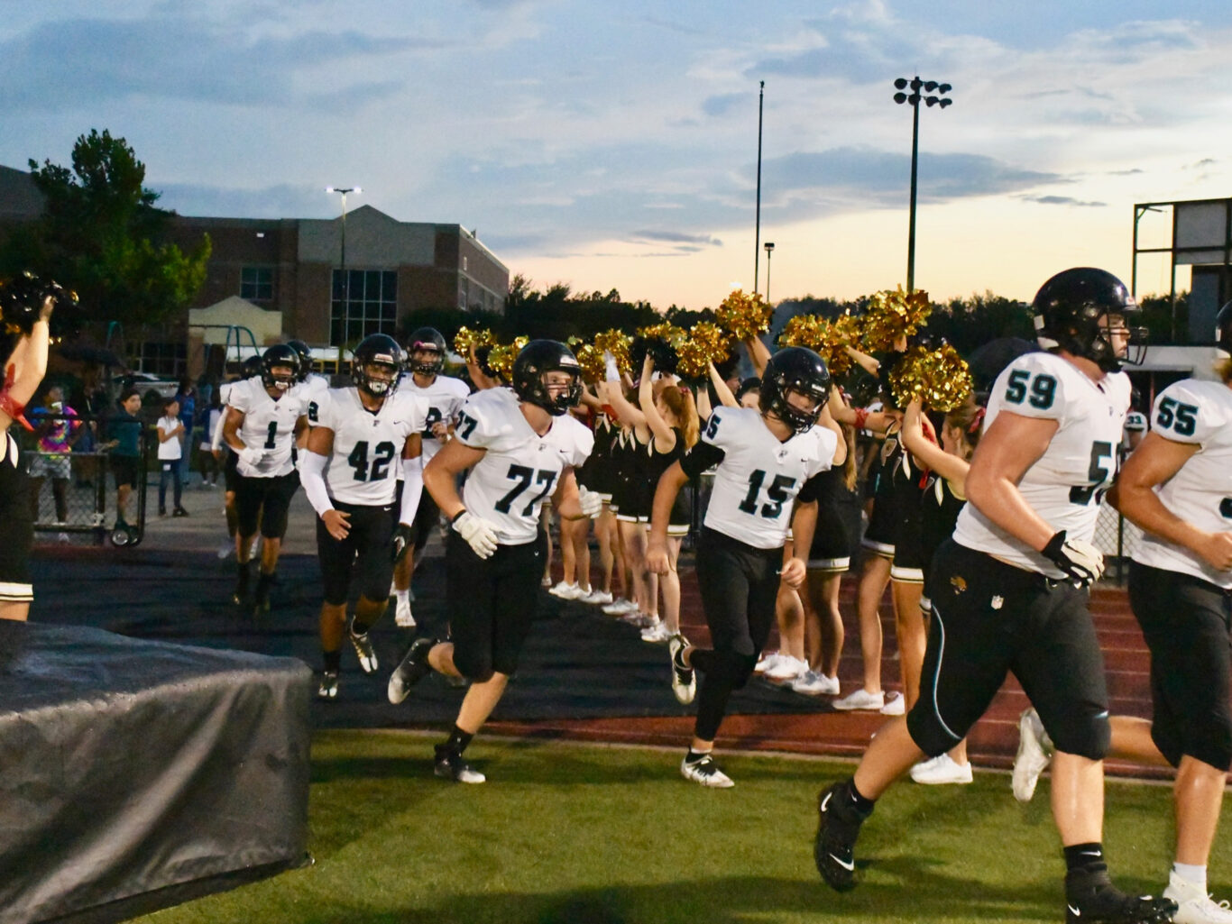 A group of football players lively walking onto the field.