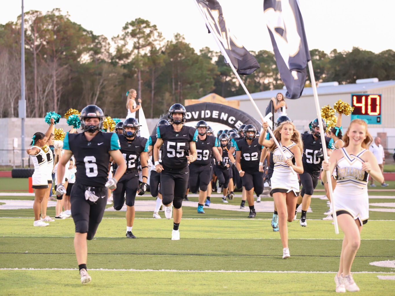 A group of football players sprinting onto the field.