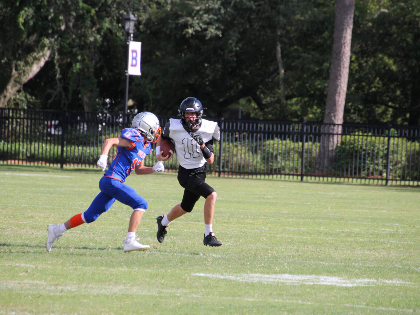 A young man sprinting with a football across a field.