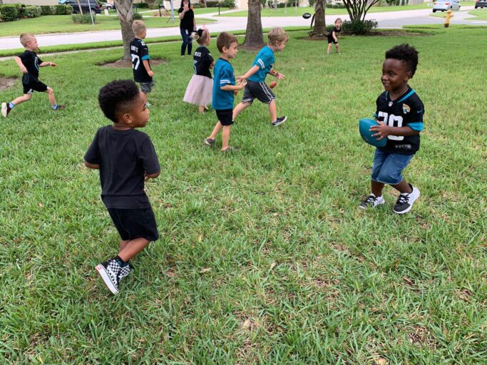 A group of children playing football in a grassy area during their gameplay break time.