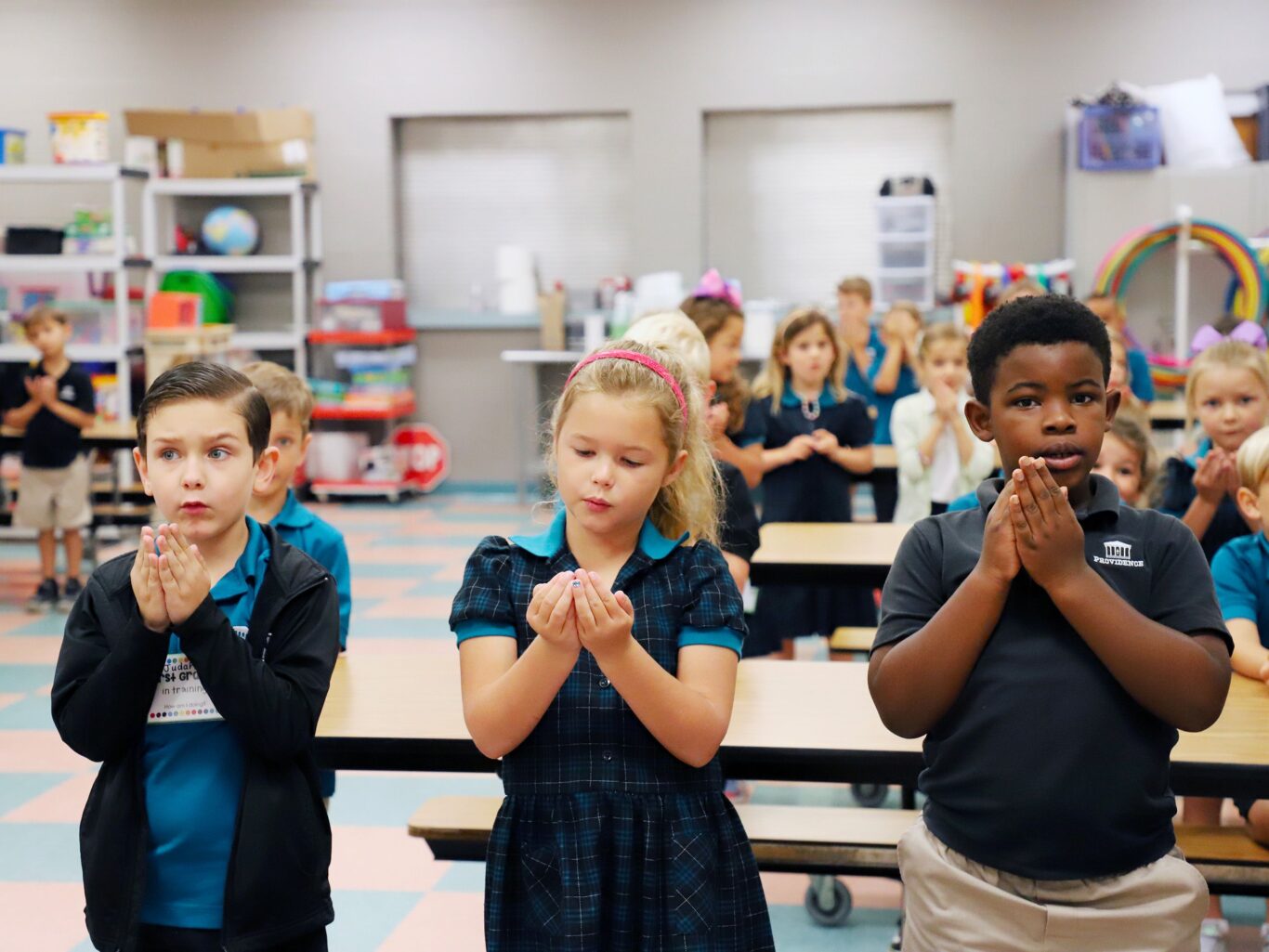 A crowd of children clapping in a classroom.