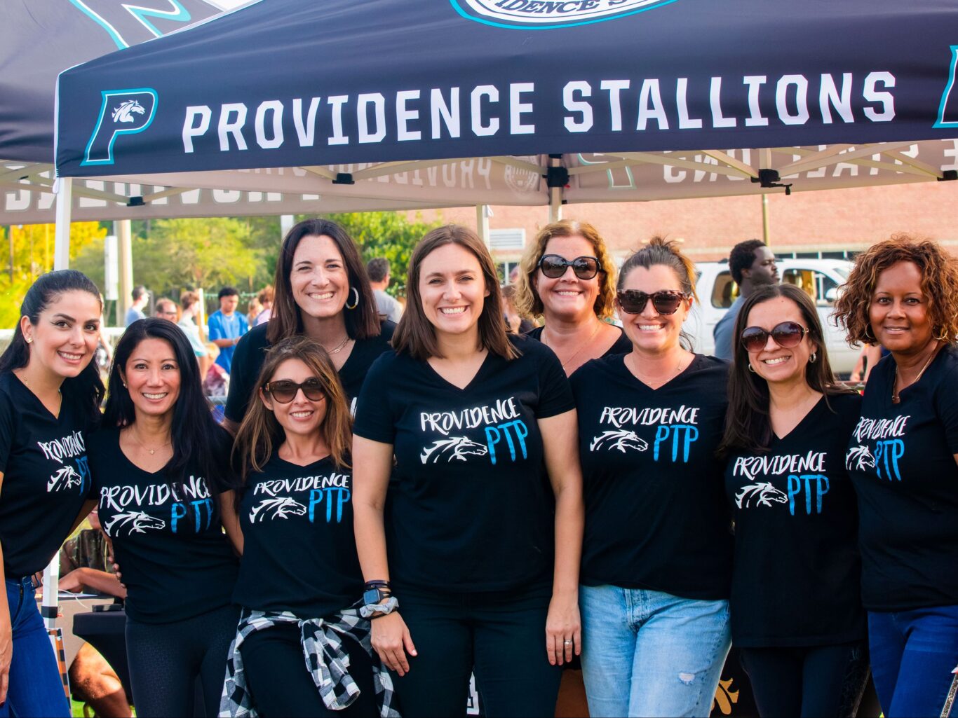 A group of women in t-shirts standing under a tent.