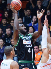 A college basketball player is trying to block a shot.