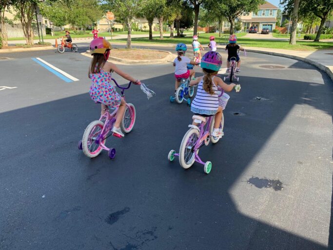 A group of children riding bikes in a parking lot during a school field trip.