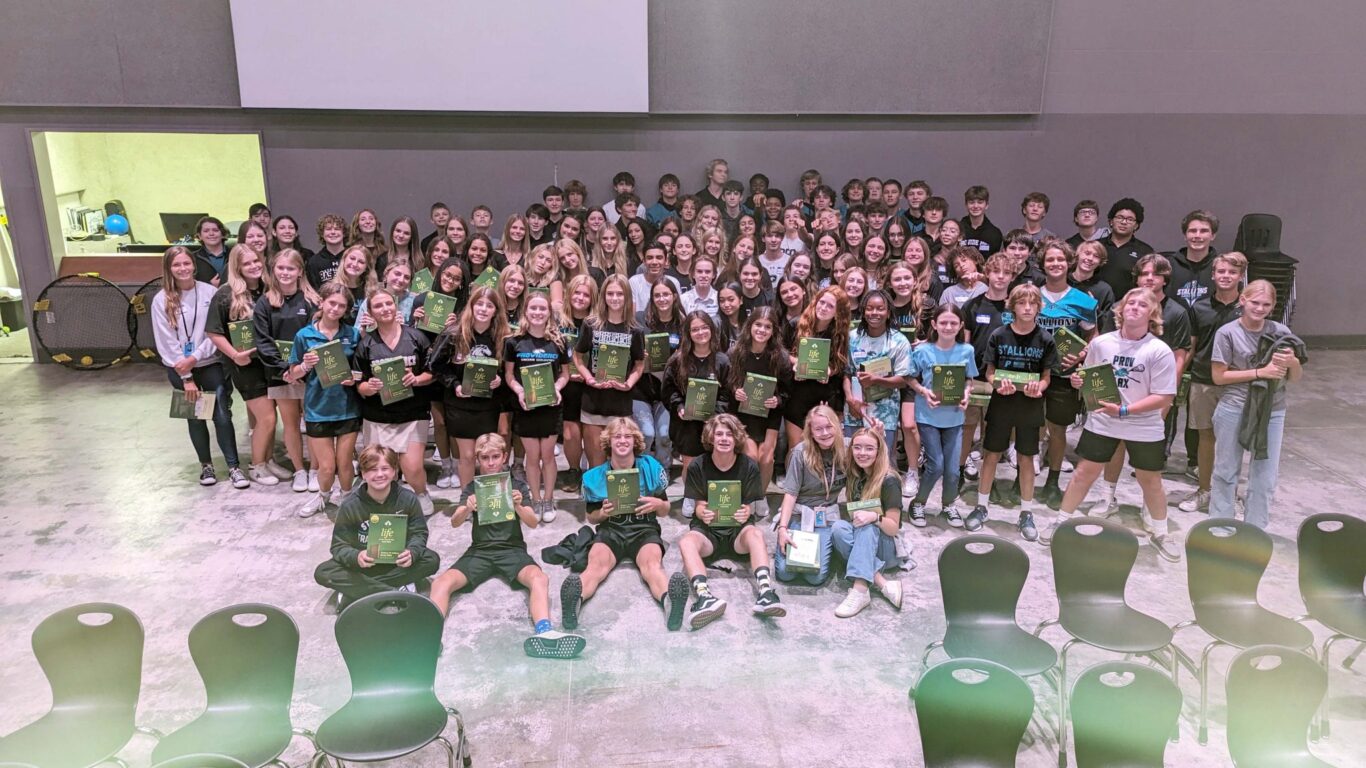 Freshman Retreat participants posing for a picture in an auditorium.