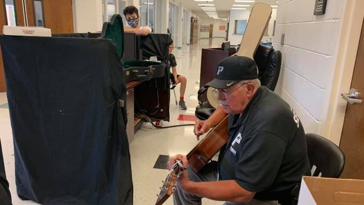 Mr. Larry playing a guitar in a hallway, reminiscent of loving memories.