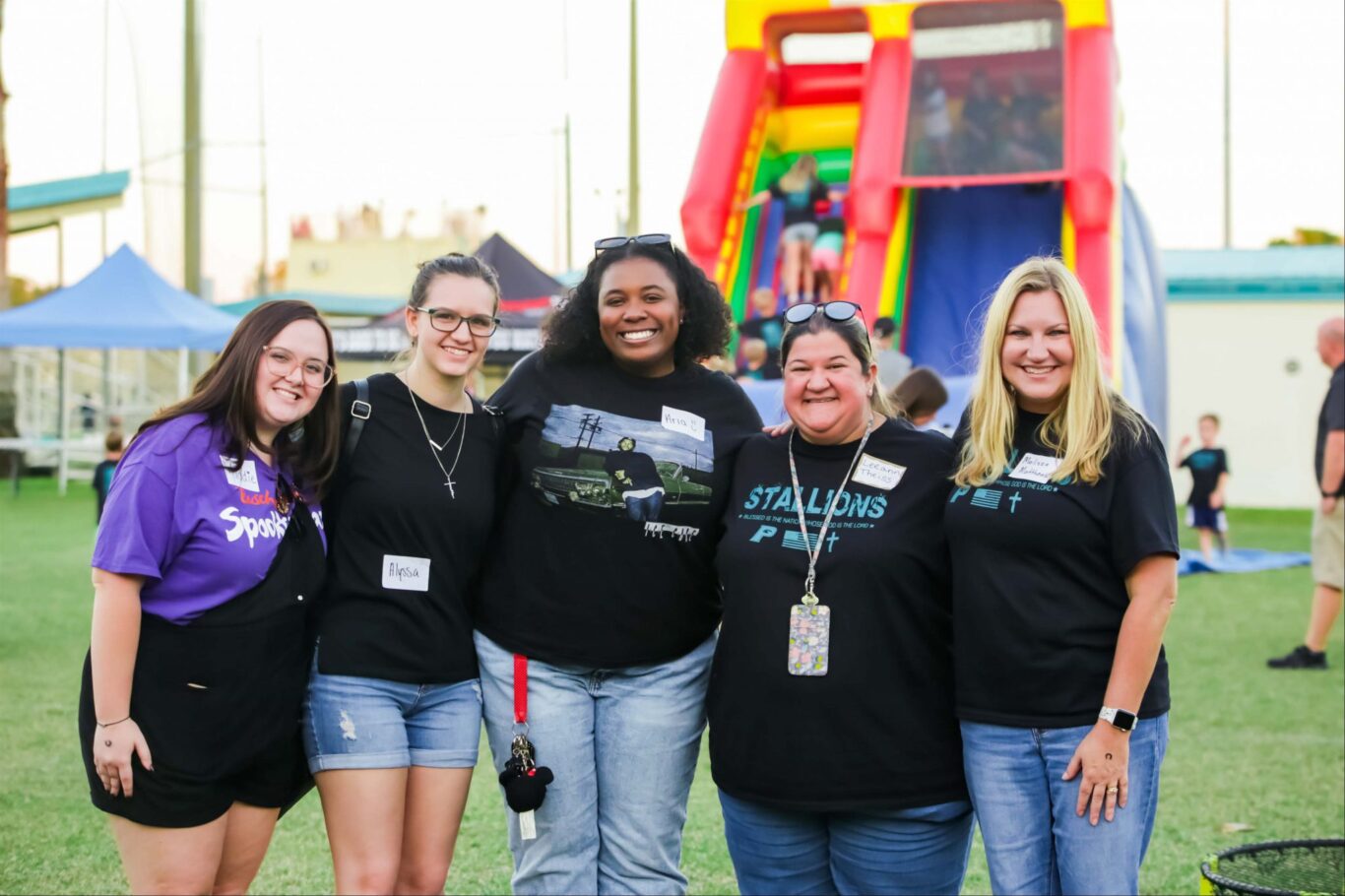 A group of women posing for a photo during Homecoming 2023 in front of a bounce house.