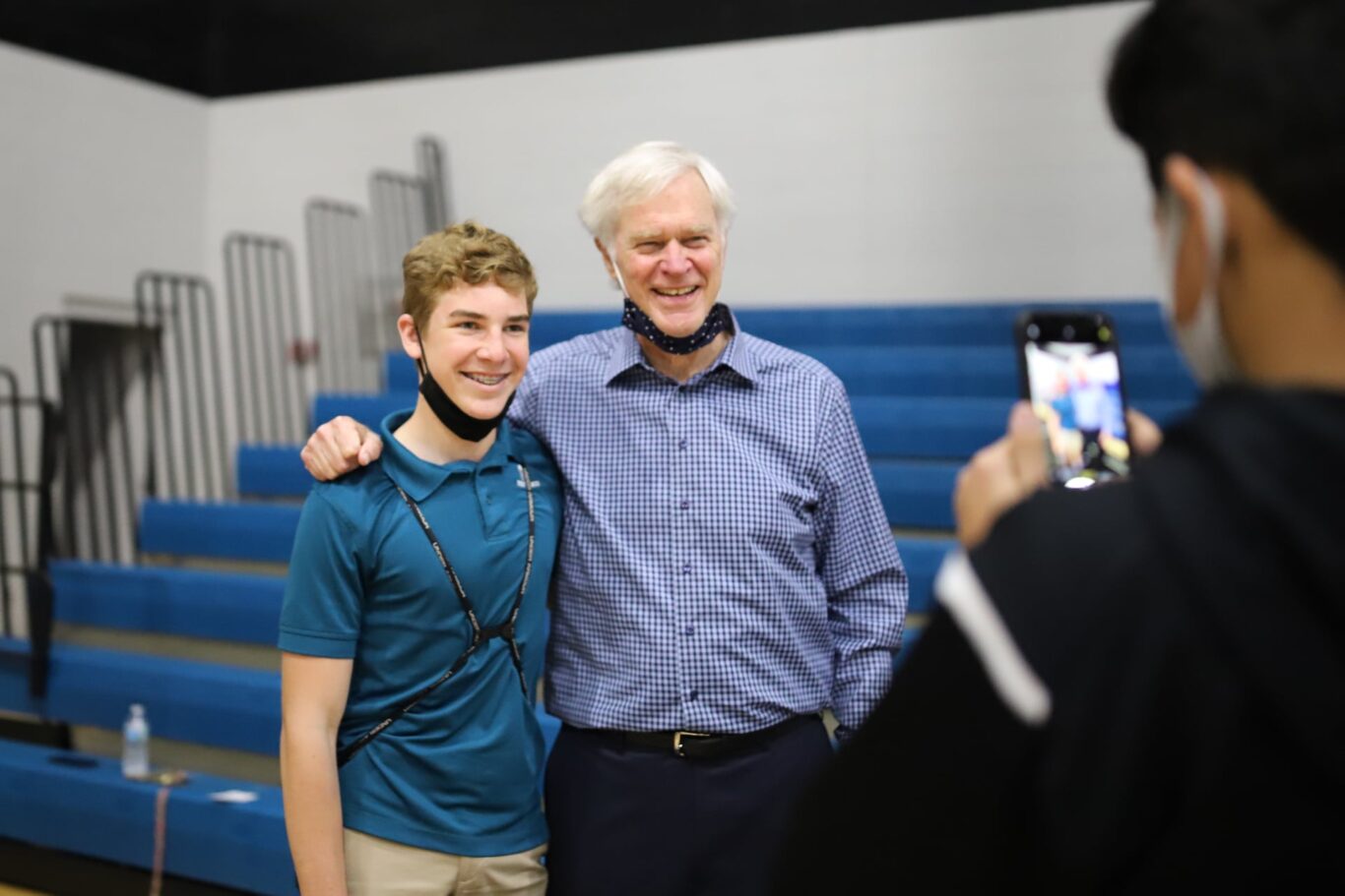 A man is taking a selfie with a young man while engaging in an action-packed workout session at the gym.