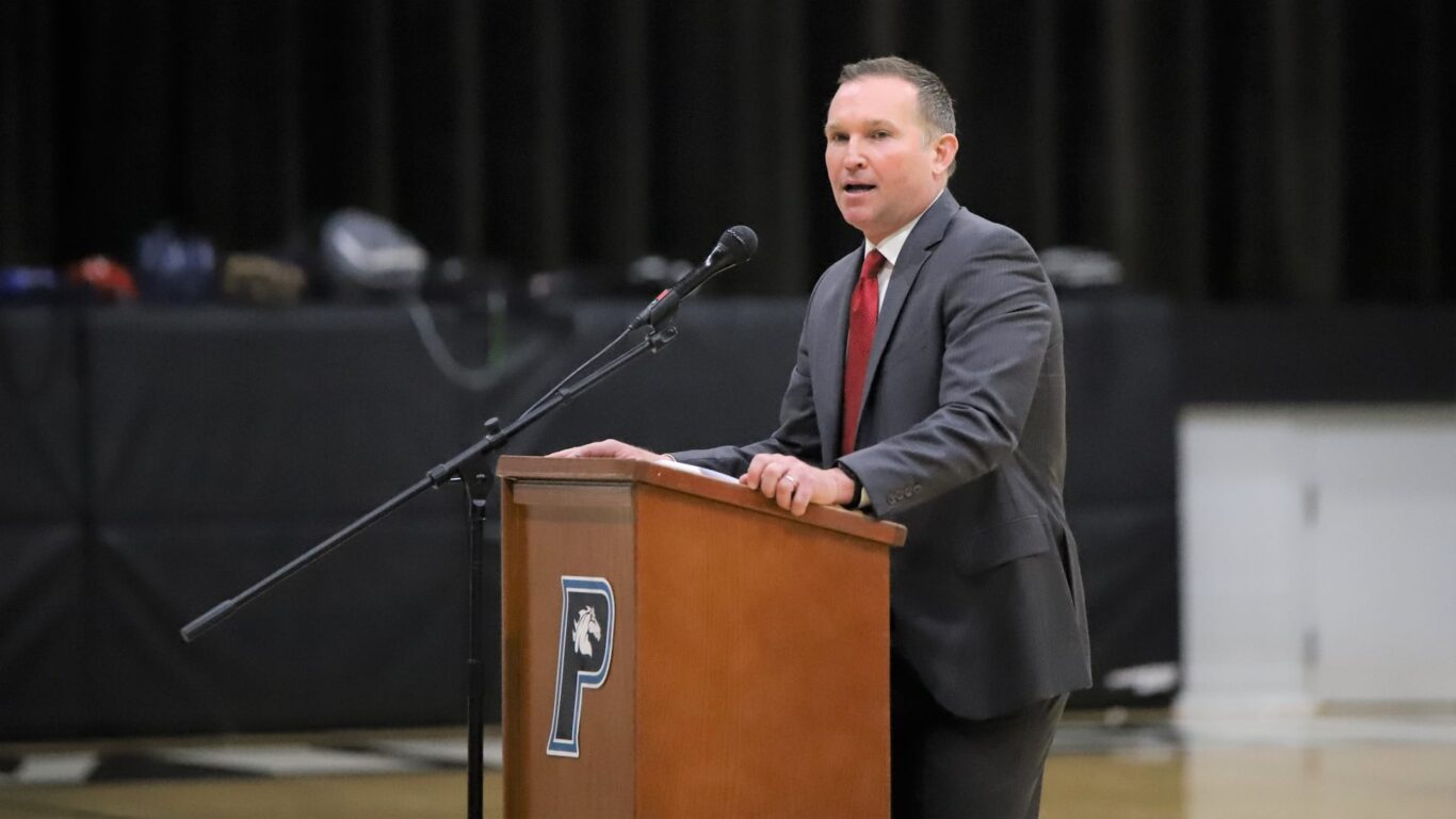 A man in a suit taking action at a podium during a civics event.