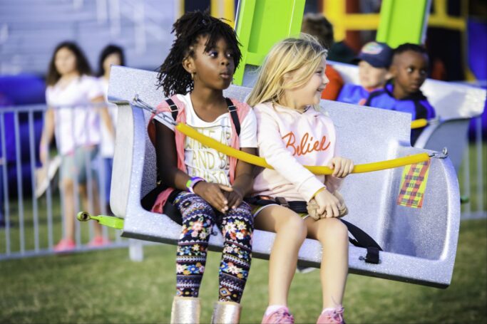 Two girls sitting on a swing at the PTP Fall Festival in 2023.