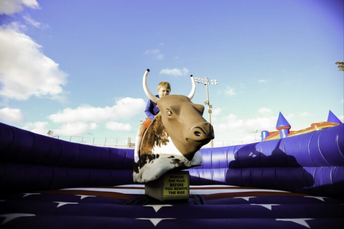 A girl riding a bull at the PTP Fall Festival in 2023 on an inflatable.