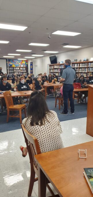 In a library, a group of people sits at tables while visiting Providence and listening to the insightful stories of NY Times bestselling author Charles Martin.