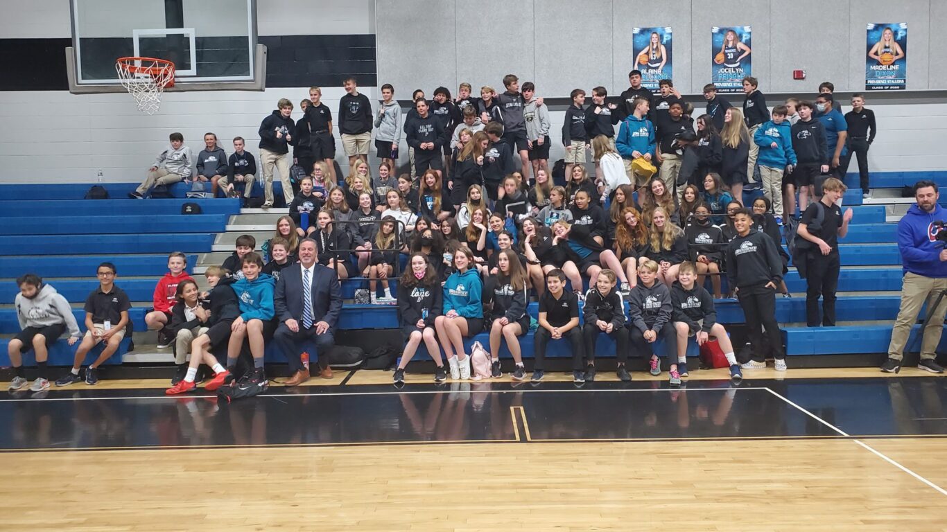 A group of people participating in a civics activity by posing for a photo in a gym.