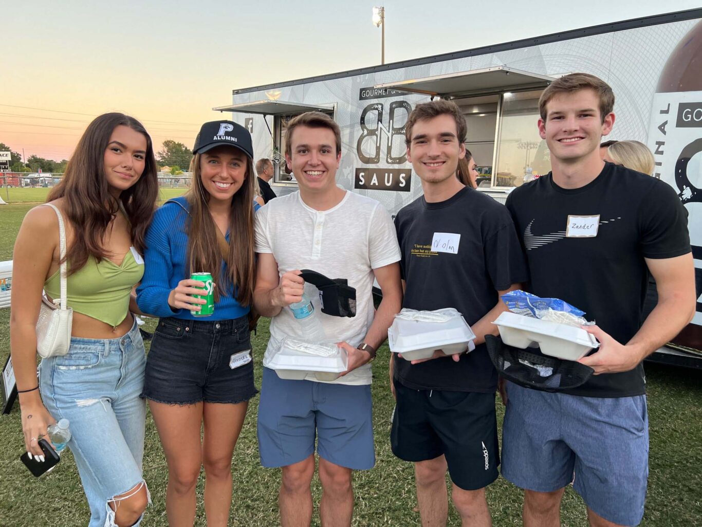 A group of people standing in front of a food truck at Homecoming 2023.