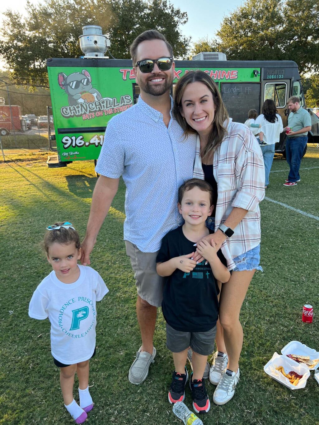 A family posing for a homecoming photo in front of a food truck.